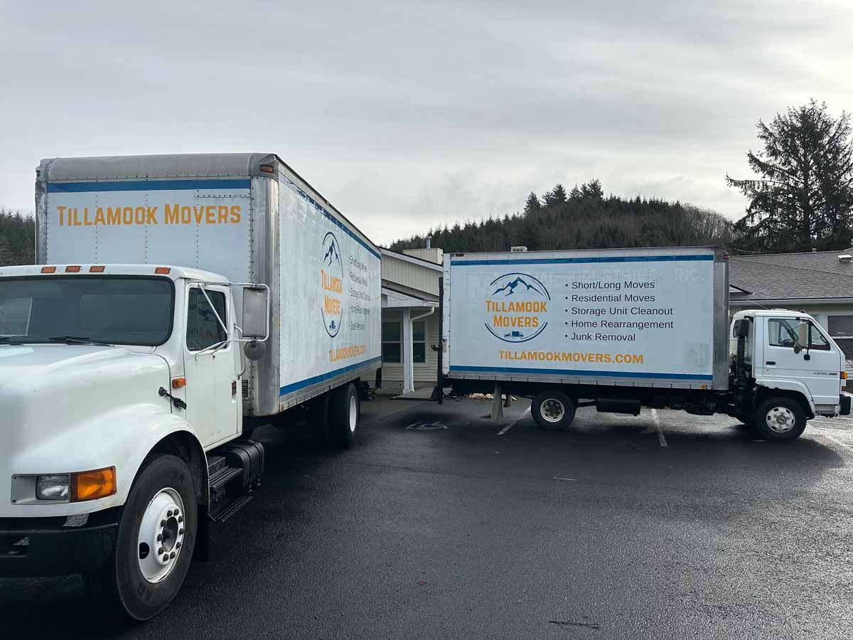 Two moving trucks are parked next to each other in a parking lot.