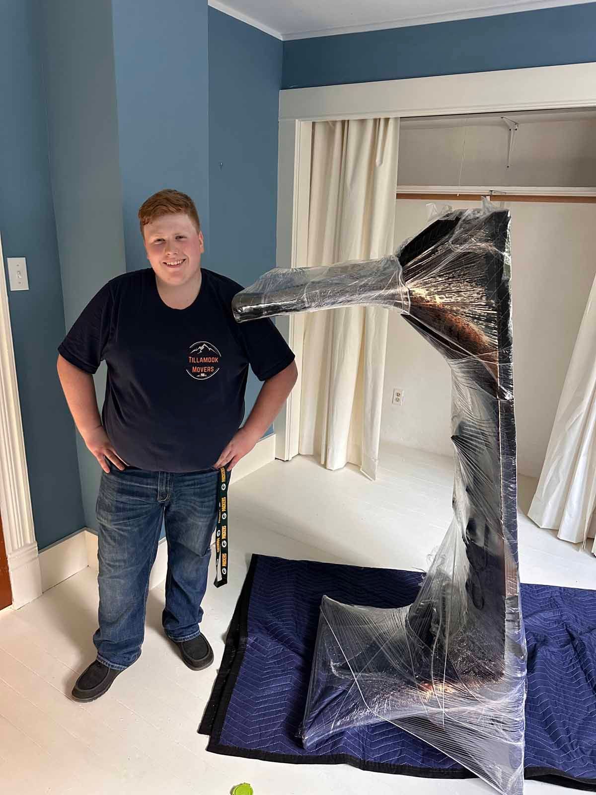 A man is standing next to a large object wrapped in plastic.