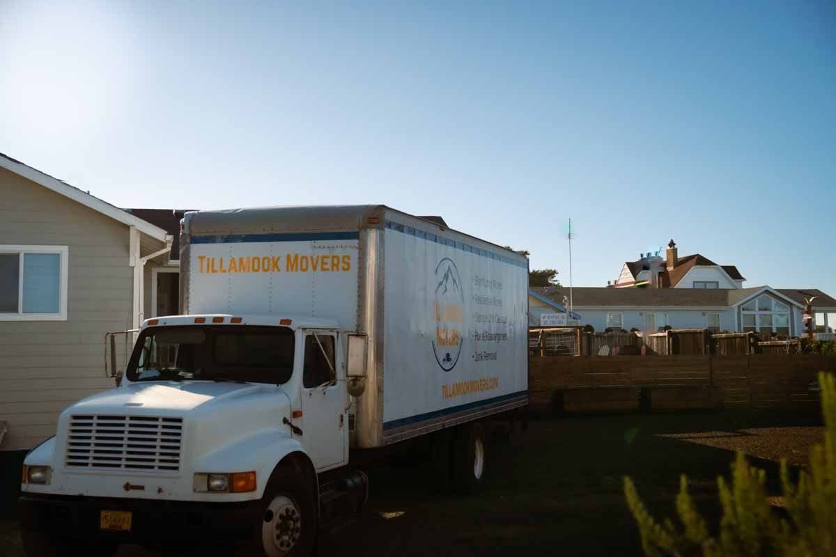 A white moving truck is parked in front of a house.