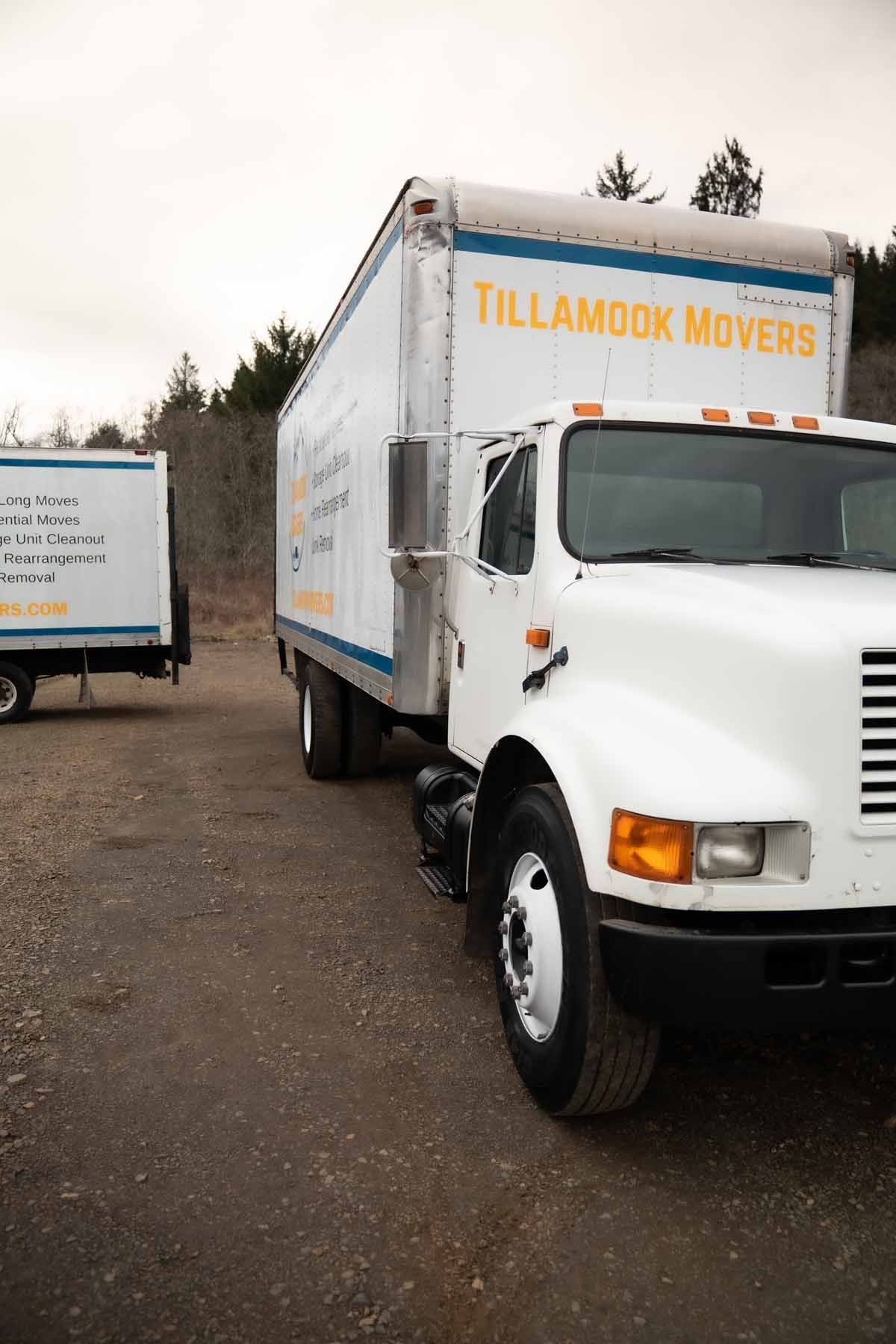 A white moving truck is parked next to a trailer.