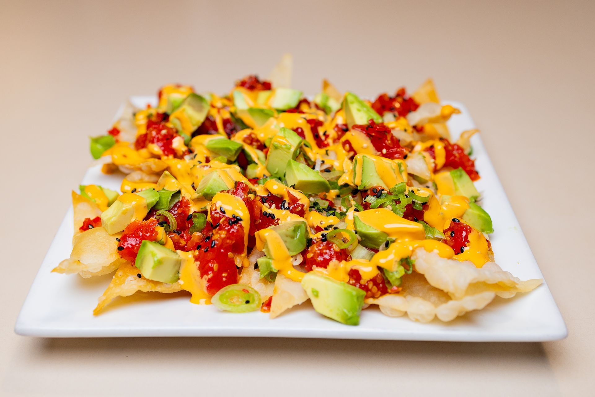 A white plate topped with POKE nachos , avocado , cheese and sauce.