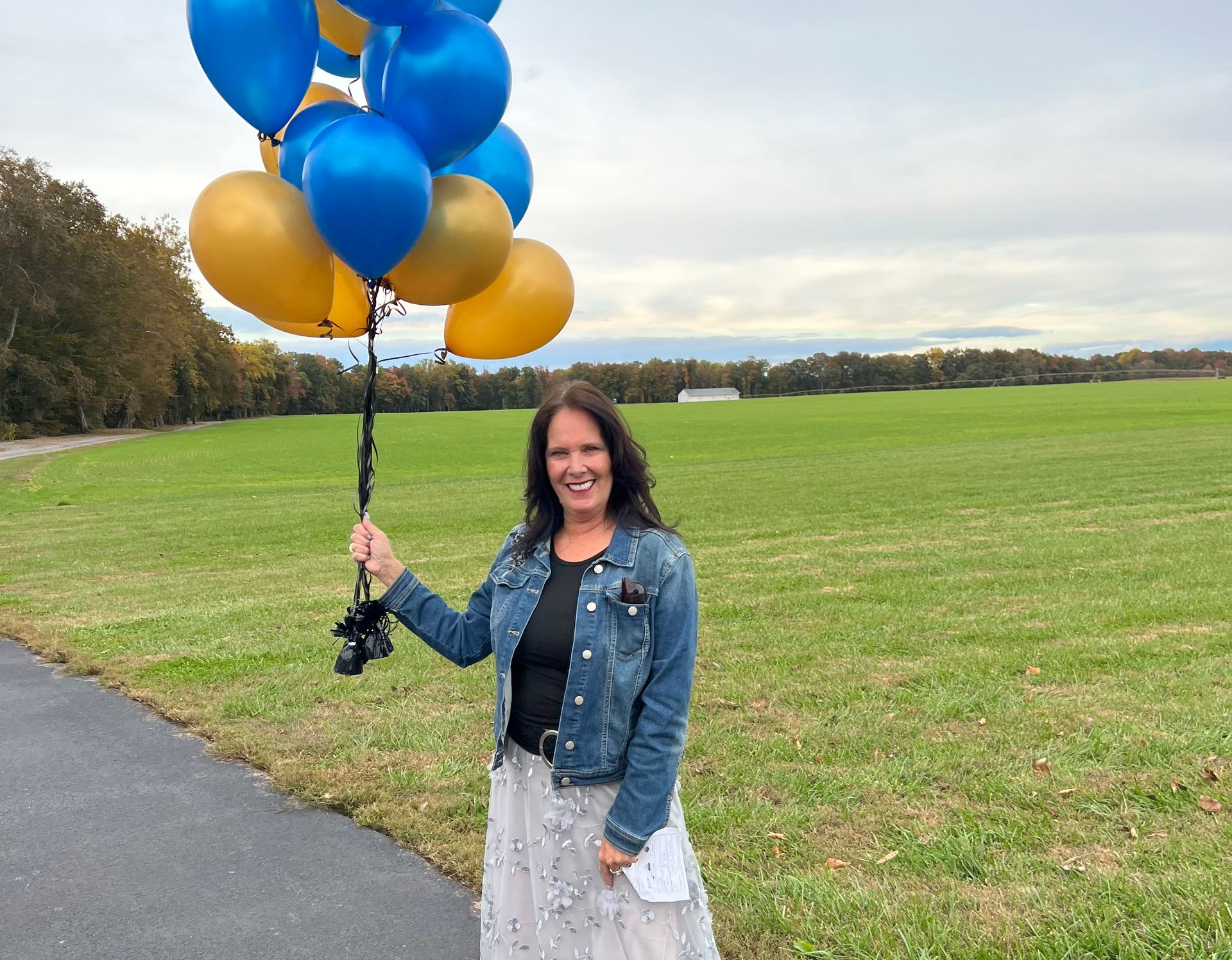 Senator Kyra Hoffner holding yellow and blue balloons outside