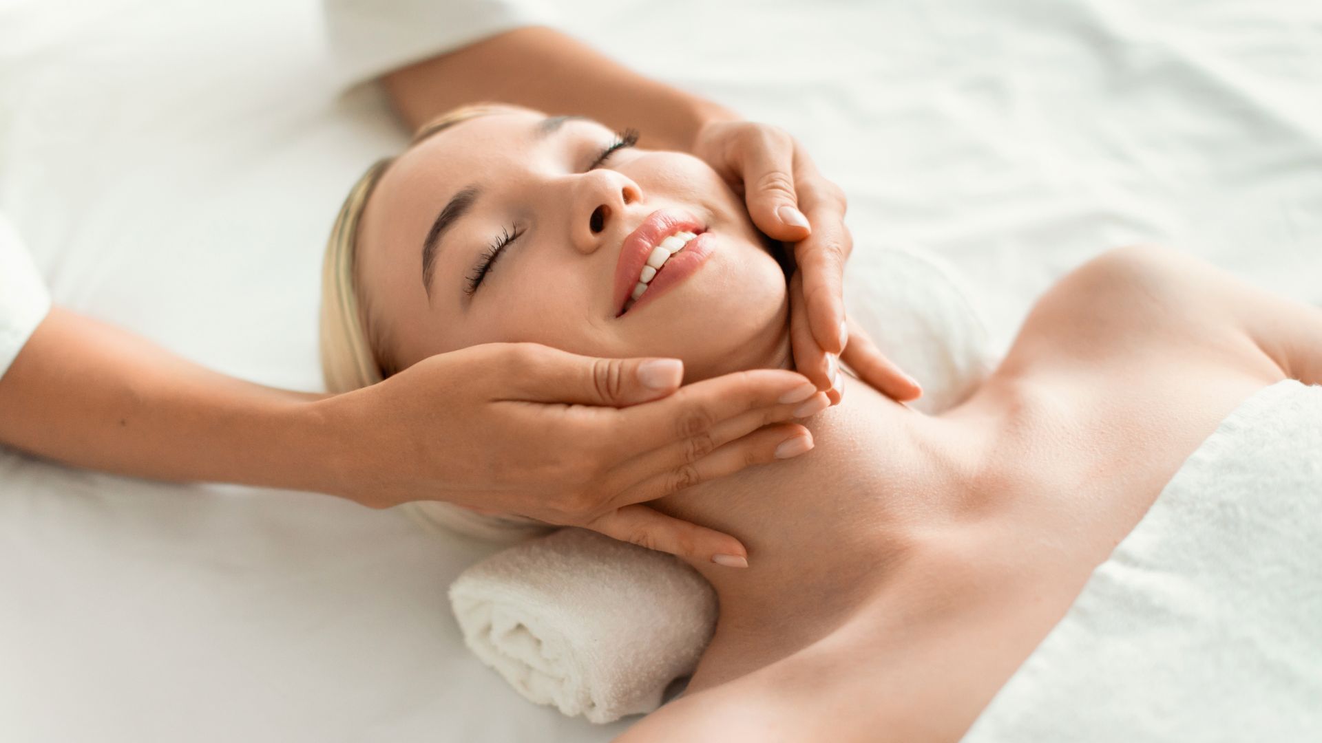 A person lying down receiving a relaxing facial massage in a spa setting.