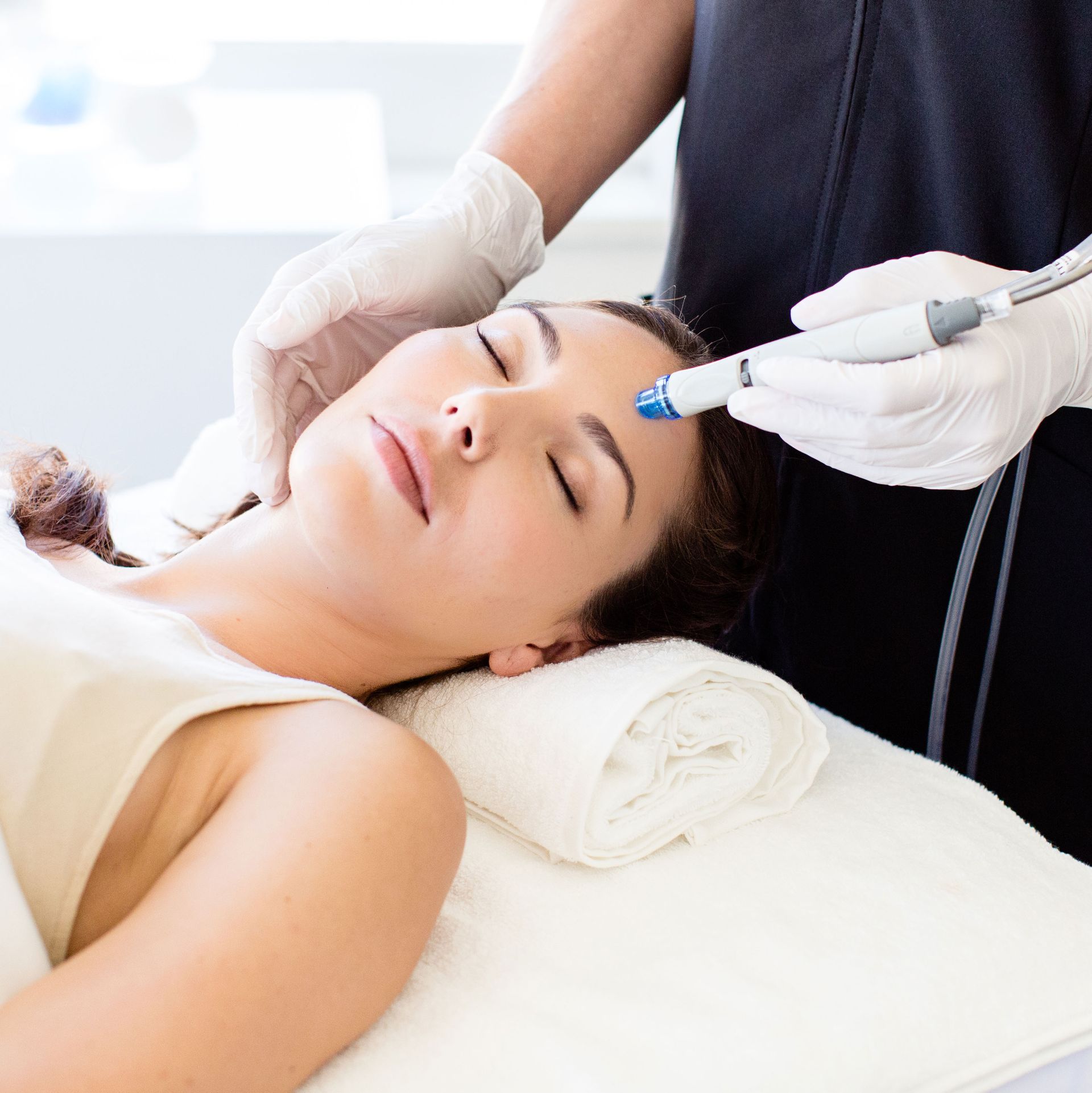 A woman is laying on a bed getting a facial treatment.