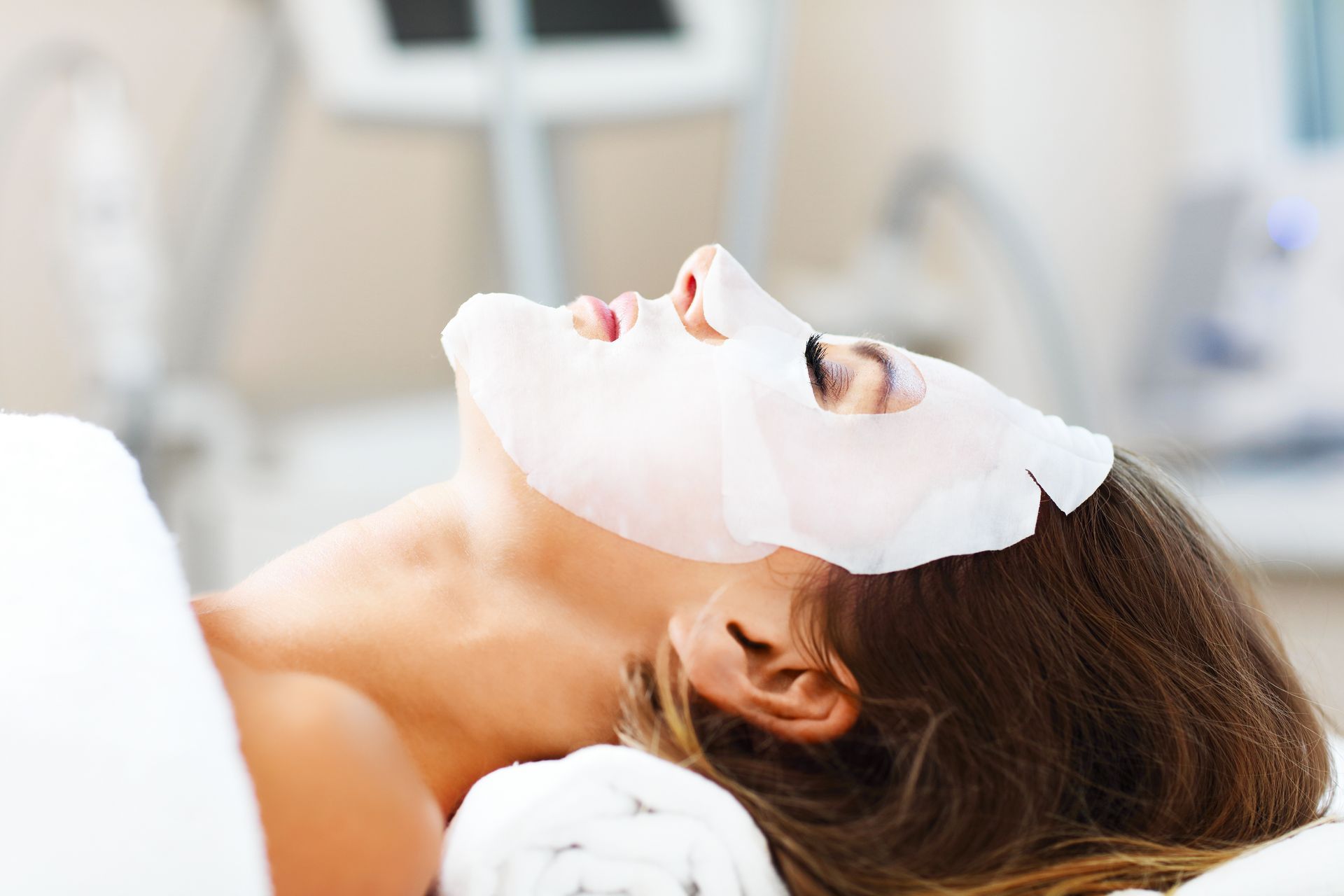 Woman wearing a face mask, lying down in a spa setting.