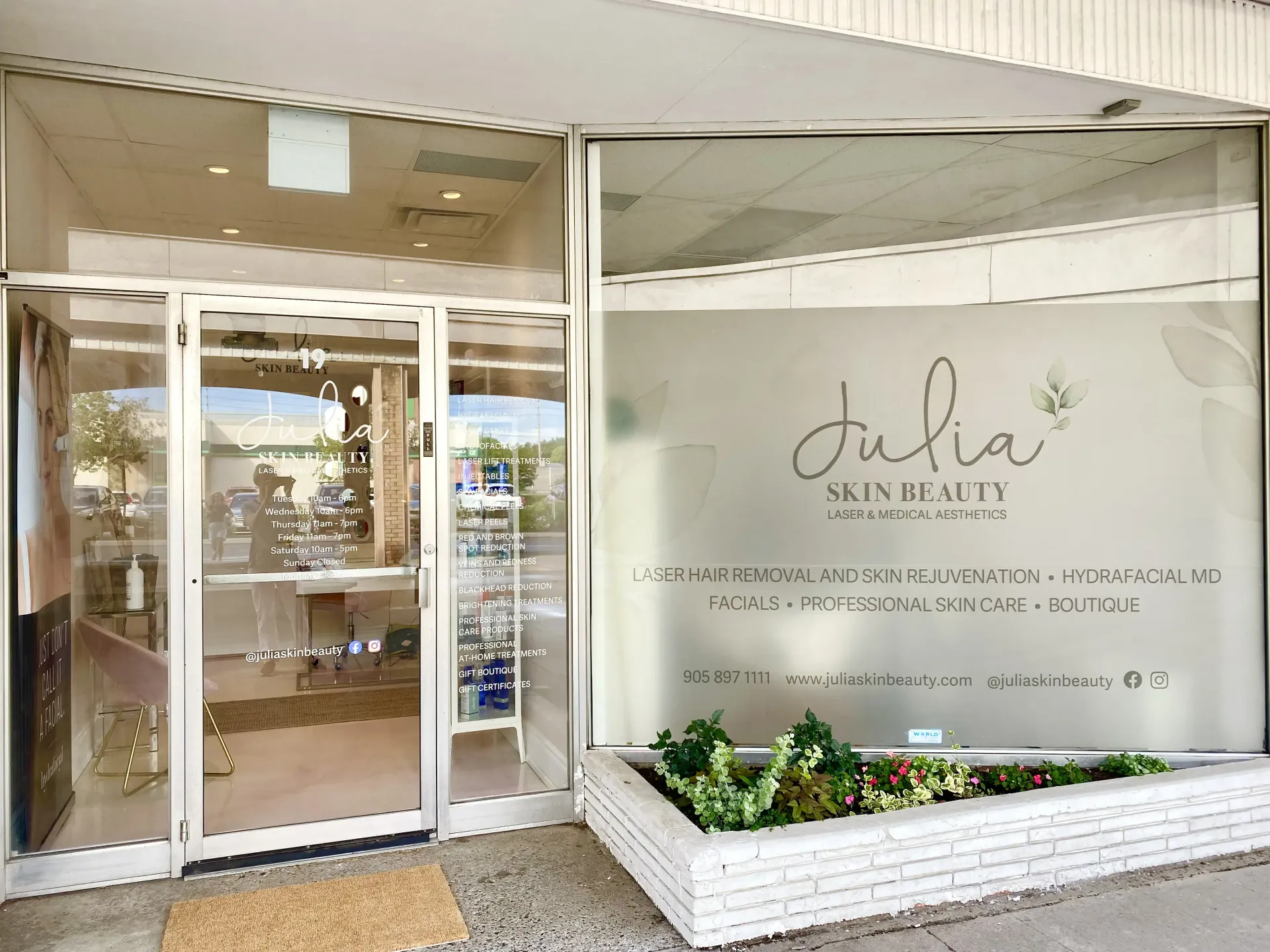 The front of a beauty salon with a planter in front of it.