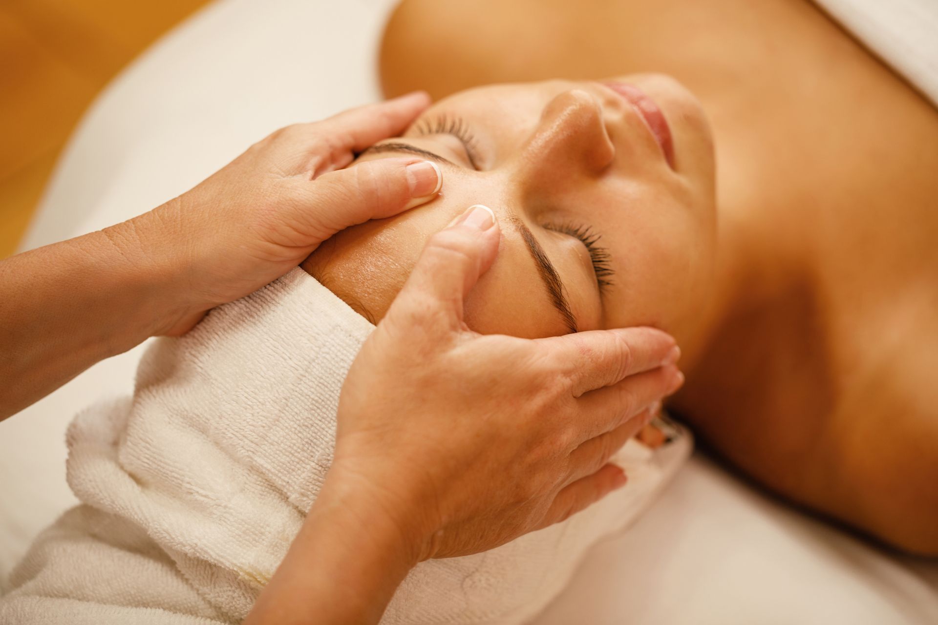 A woman is getting a facial massage at a spa.