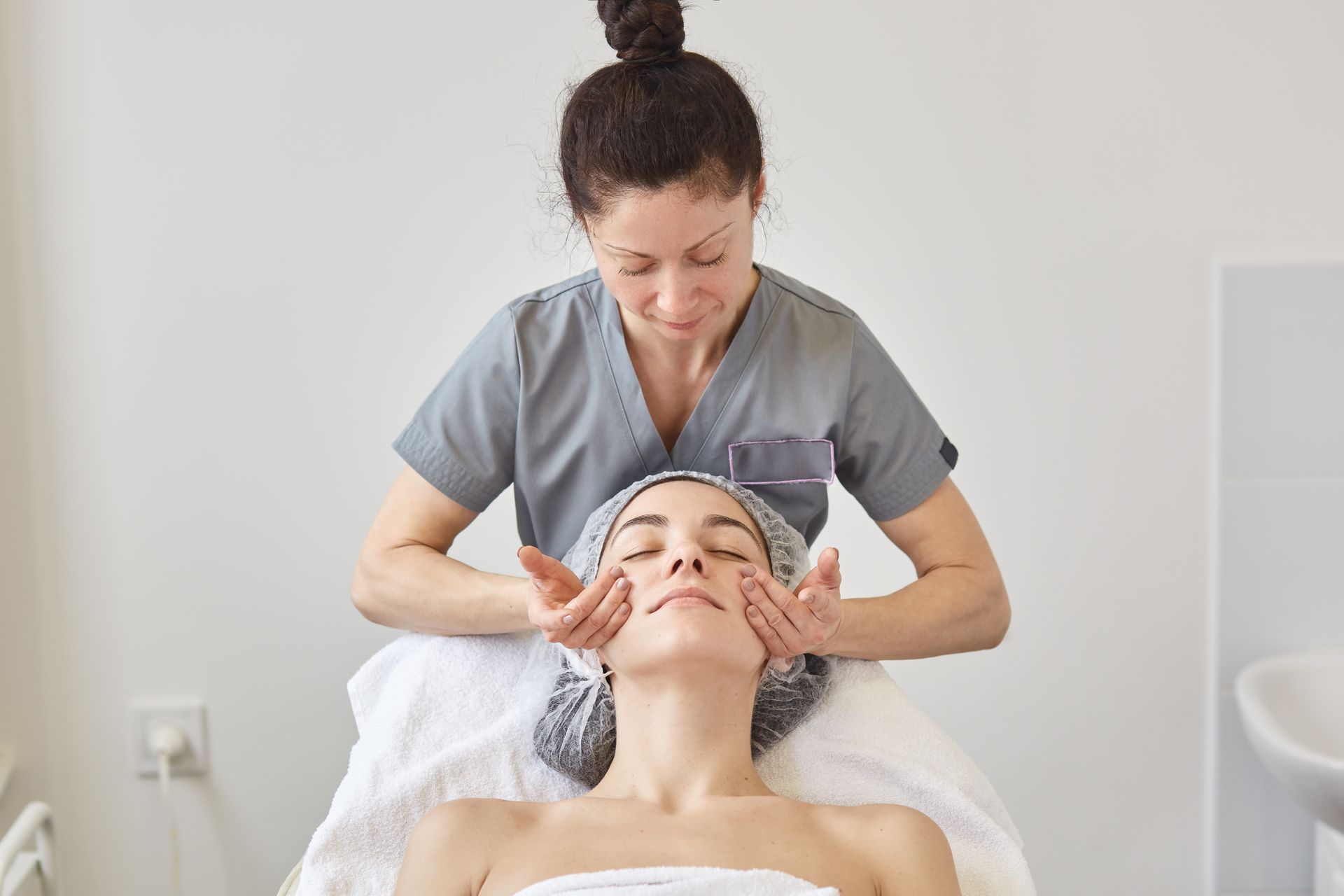 A woman is getting a facial massage at a spa.