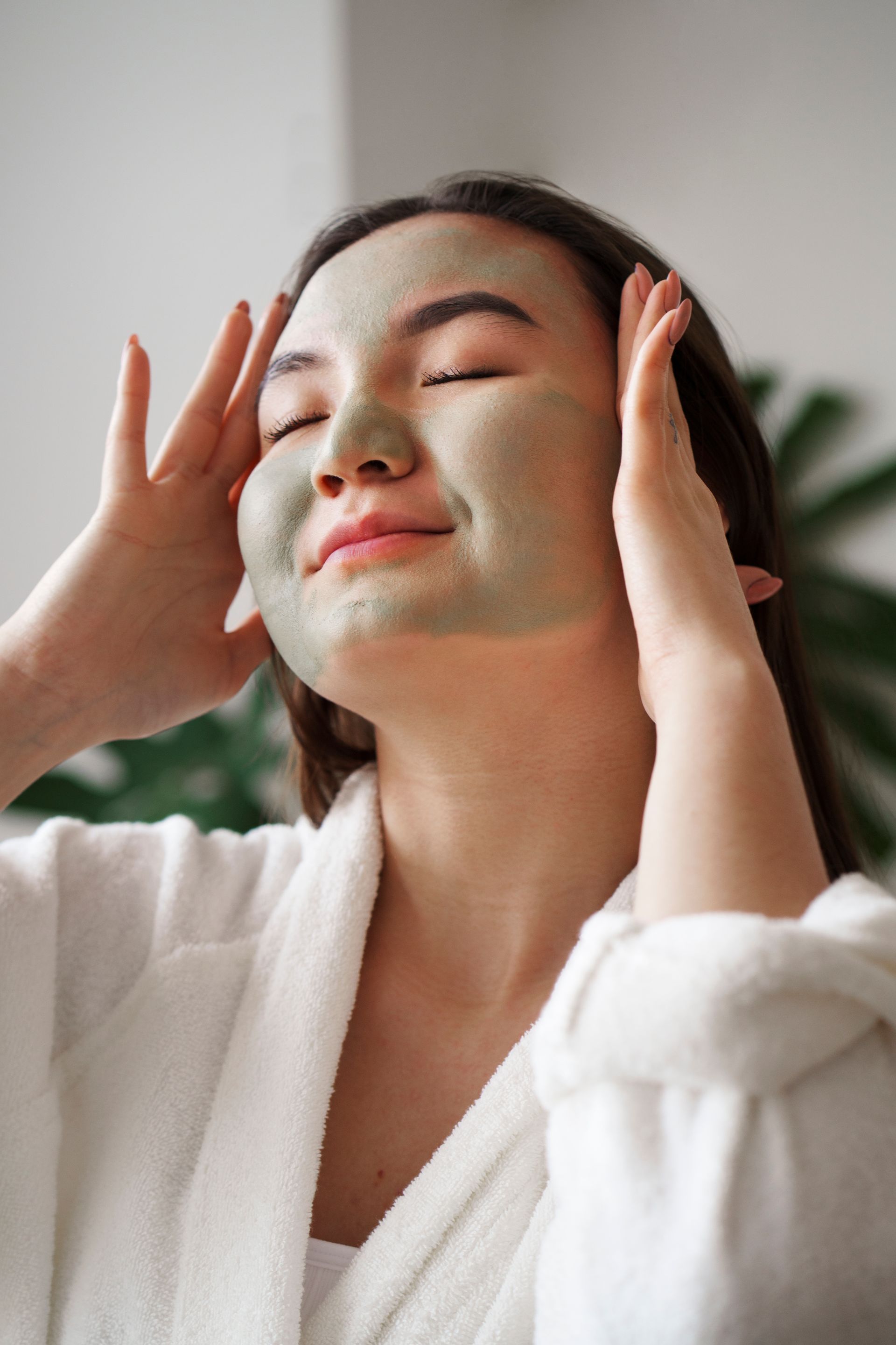 A woman is wearing a green clay mask on her face.