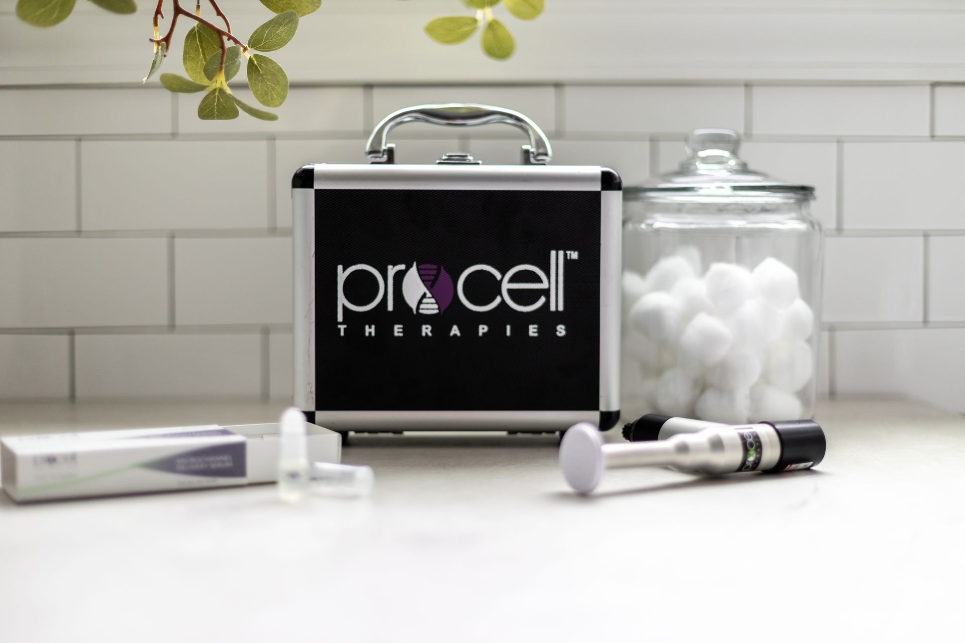 A case with the word pro cell on it is sitting on a counter next to a jar of cotton balls.