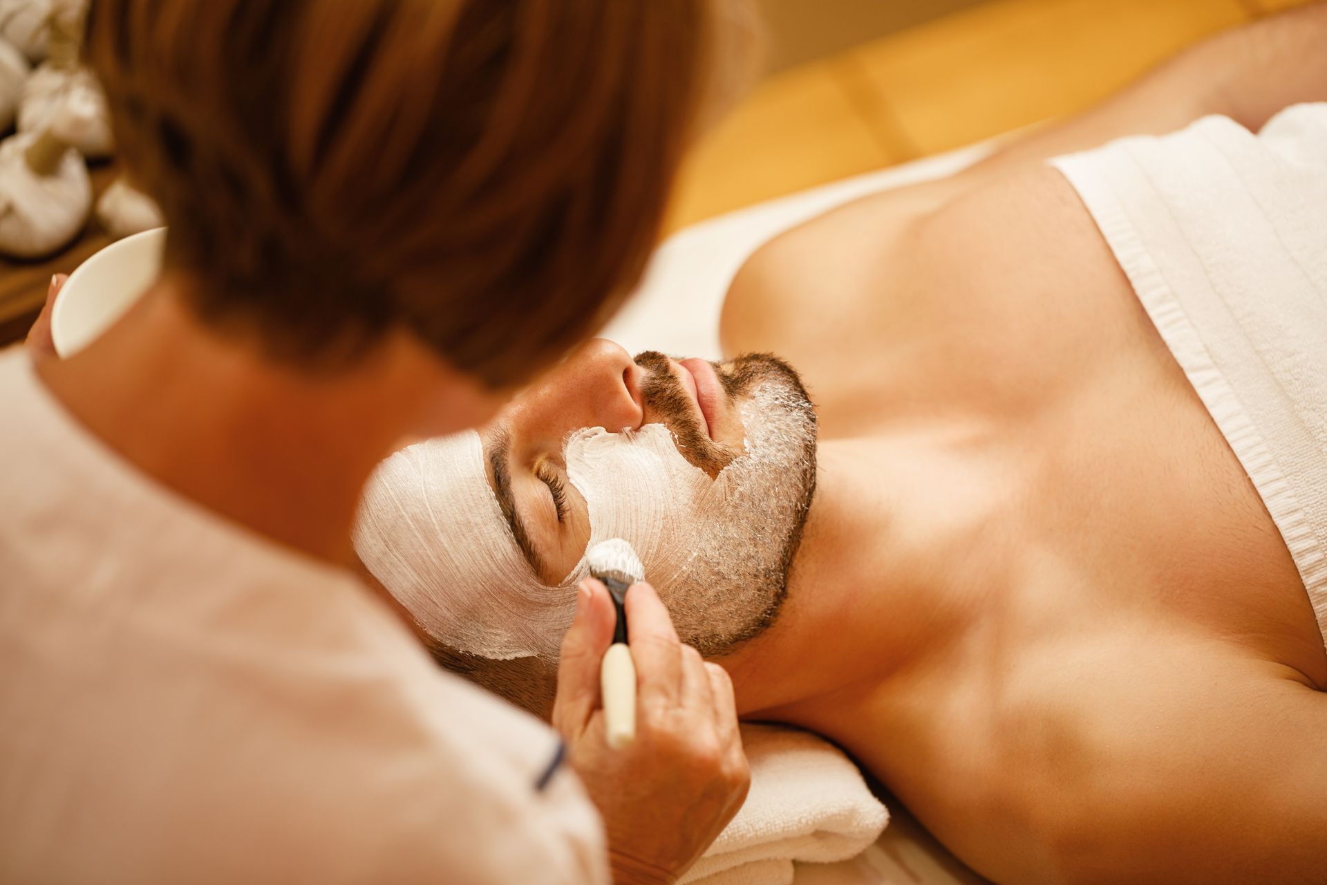 A man is getting a facial treatment at a spa.