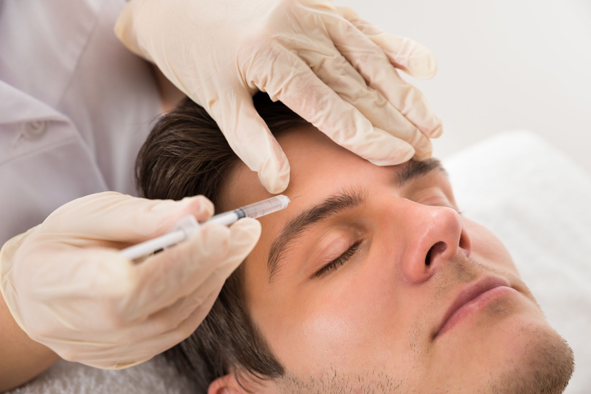 A man is getting a botox injection in his forehead.