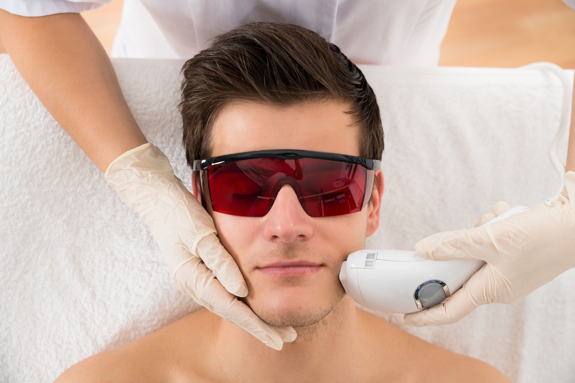 A man is getting a laser hair removal treatment on his face.