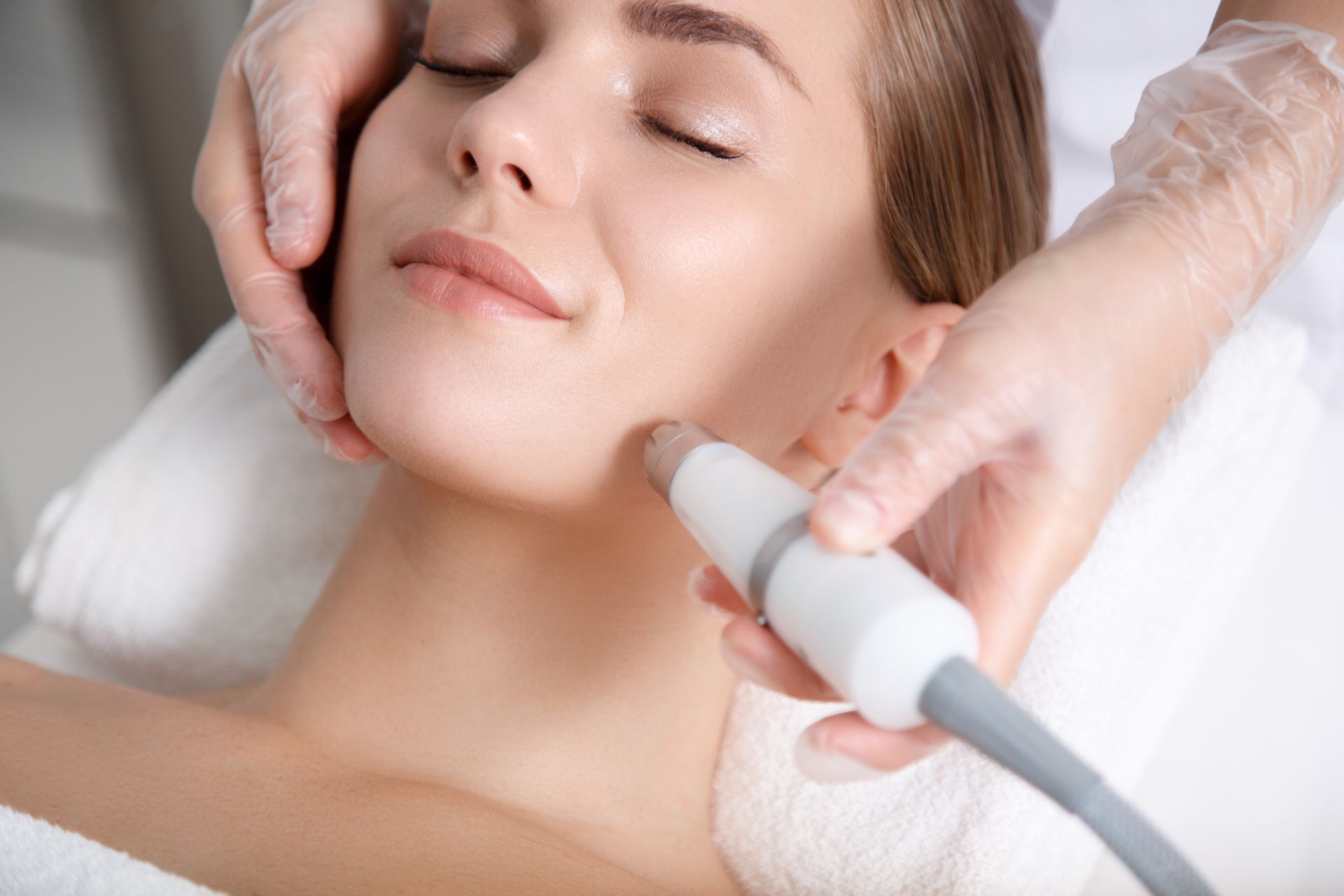 A woman is getting a laser hair removal treatment on her face.