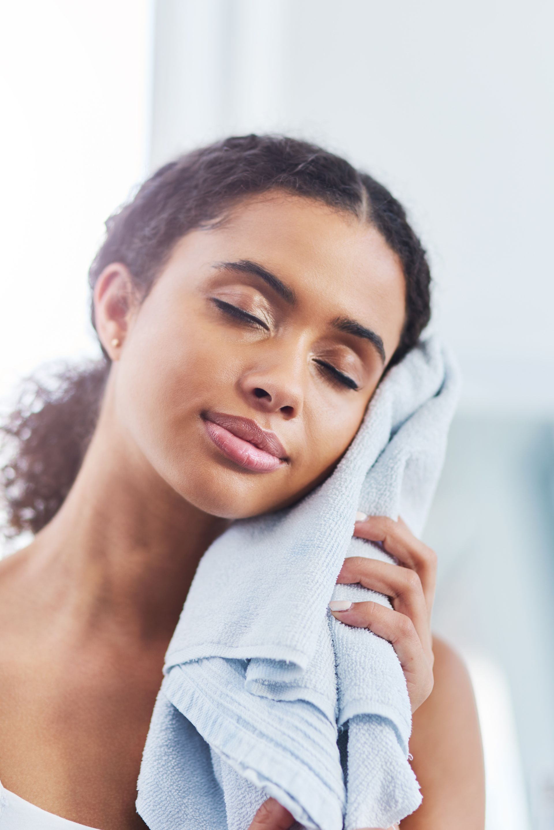 A woman is wiping her face with a towel.