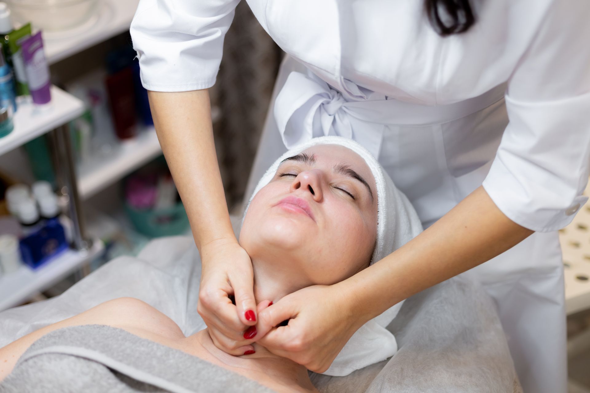 A woman is getting a massage on her neck in a beauty salon.