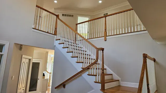 Staircase with wooden handrails and white spindles, leading to a second floor.