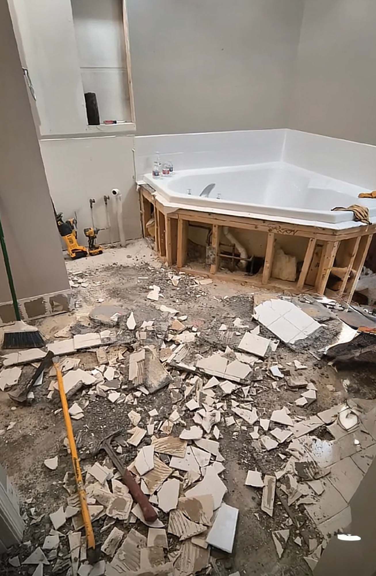 Bathroom renovation with tile debris on the floor and a partially framed-in jacuzzi tub.