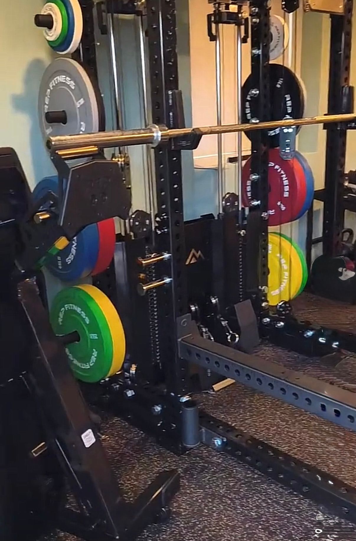 Weightlifting equipment: squat rack with barbell and weight plates, gym setting.