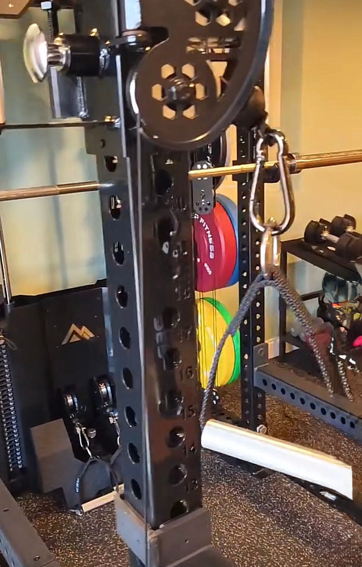 Black weight rack with attached pulley system. Carabiner clip, weight plates, and cable visible.
