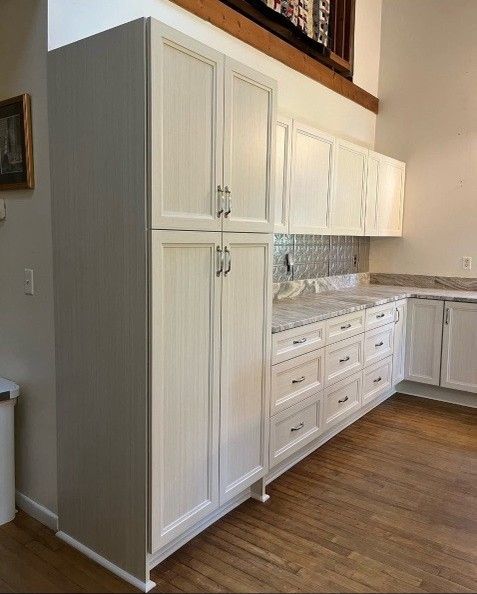 White kitchen cabinets with granite countertops and wood flooring.