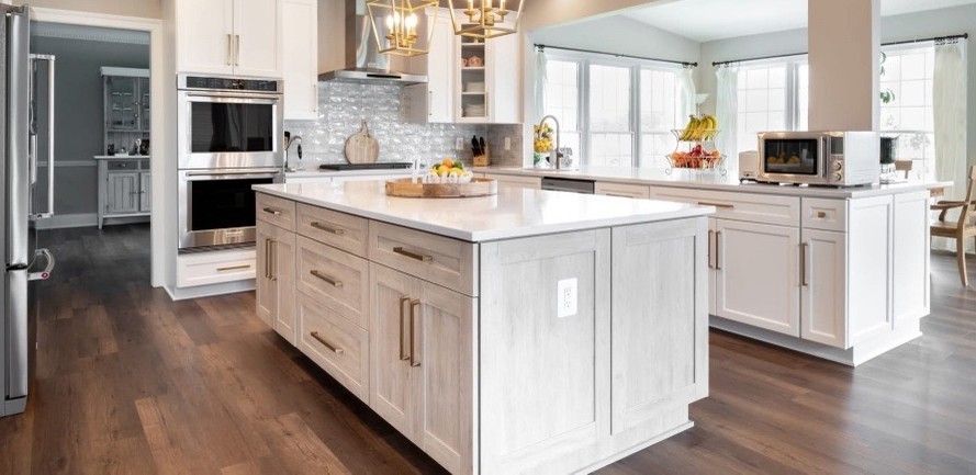 A spacious kitchen with white cabinetry, a large island, and dark wood flooring.