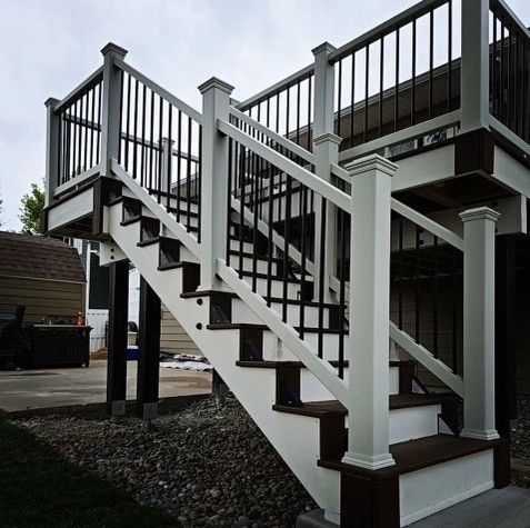 Composite deck stairs with white and brown detailing. Black railing. Outdoor setting.