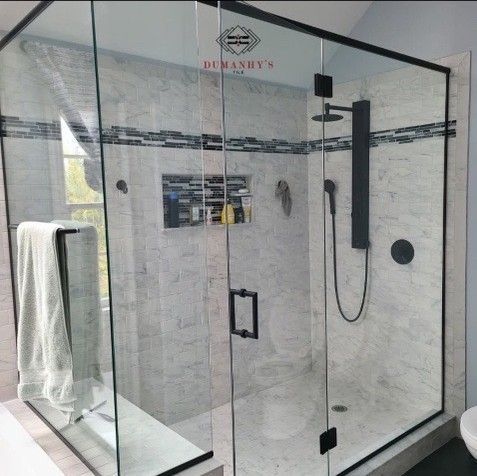 Modern shower with black-framed glass enclosure, grey tile, and black fixtures.