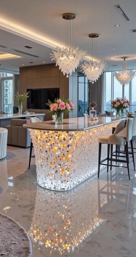 Luxurious kitchen island with illuminated, textured facade, and overhead chandeliers.