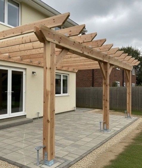 Wooden pergola over a paved patio, attached to a house with a white door and window.