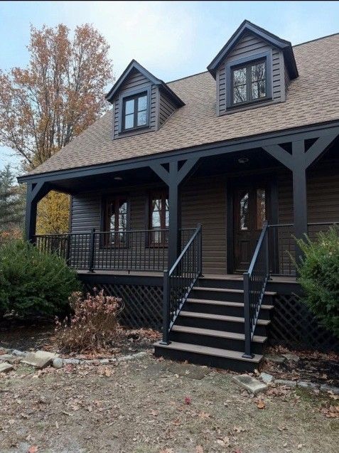 Brown house with black trim, porch, and steps; two dormers.