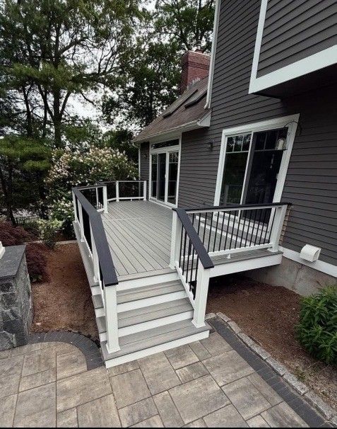 Deck with gray composite decking, black railing caps, white supports, and steps.