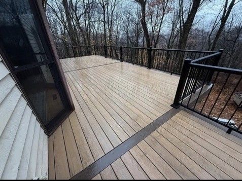 Wooden deck with black railings in a wooded setting.
