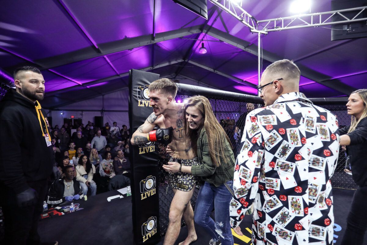 A group of people are standing around a man in a boxing ring.