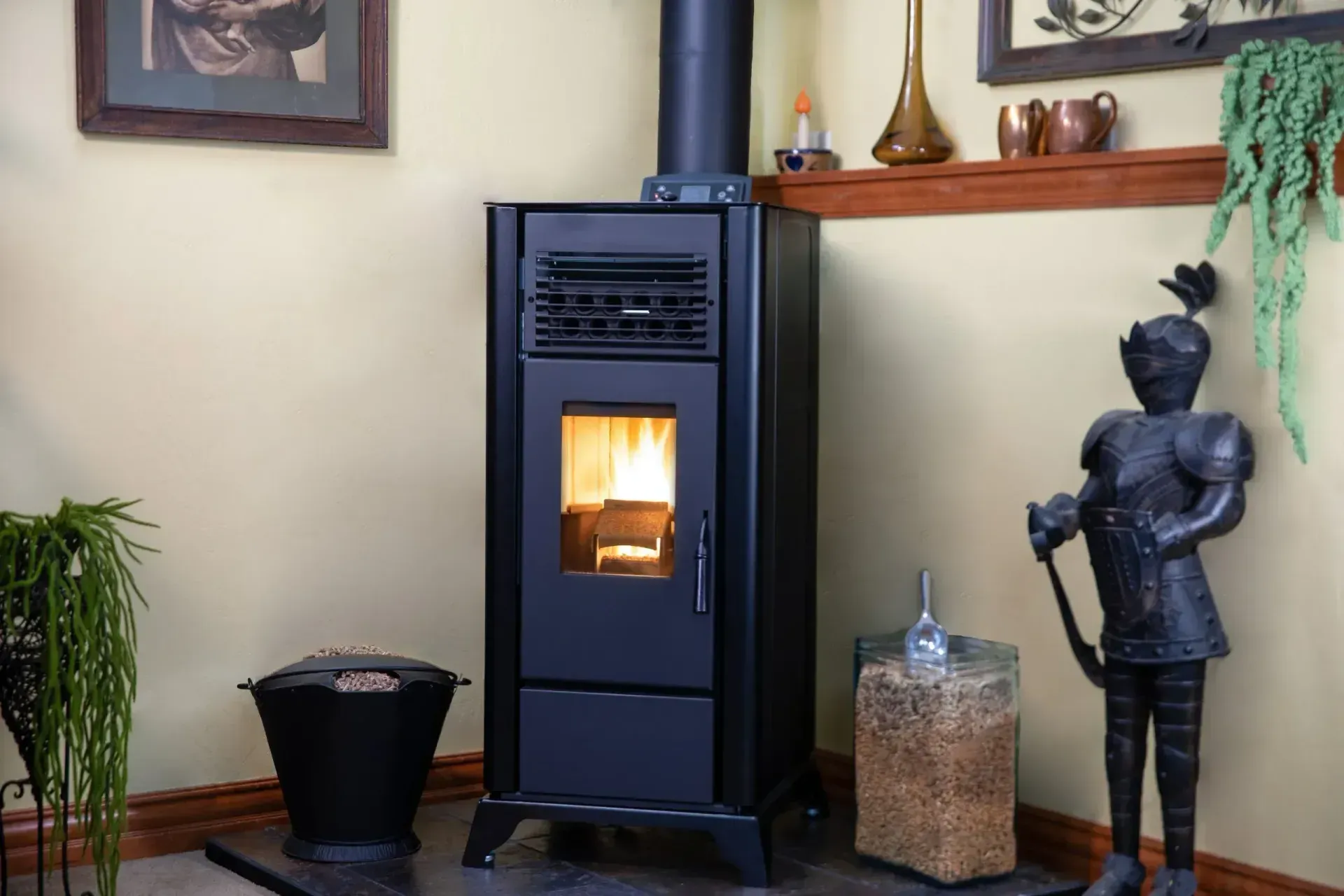 Black wood stove glowing in a cozy room, with a potted plant, statue, and decorative shelf nearby