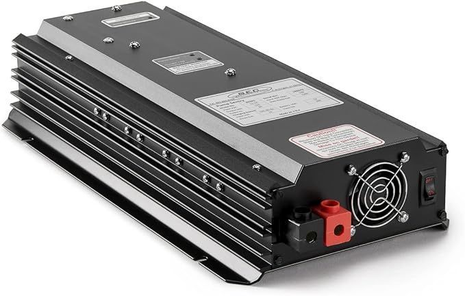 Black rectangular electronic device with cooling fins, warning labels, fan grille, and red/black terminals