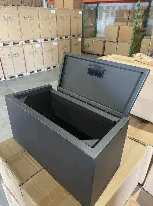 Open black storage box with hinged lid in a warehouse among stacked cardboard boxes