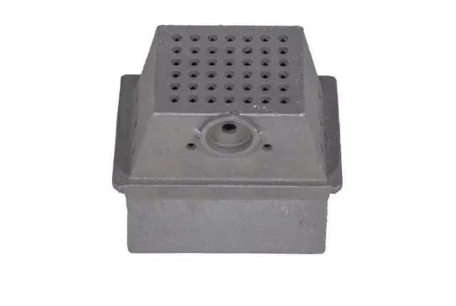 Gray metal industrial component with a perforated top and circular opening on the front