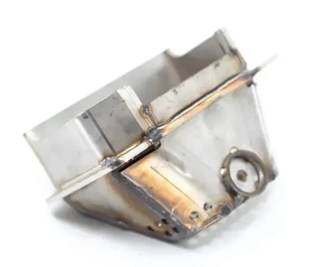 Metallic welded bracket or housing with rust stains and a circular hole on one side