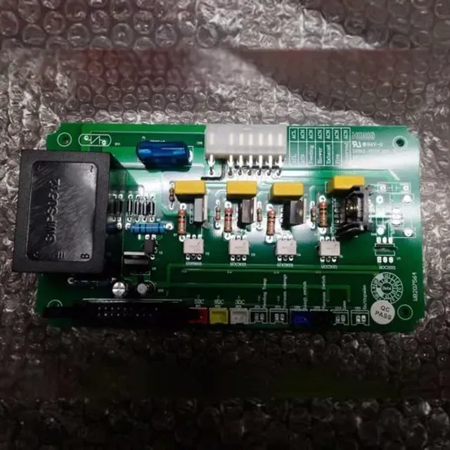 Green circuit board with black components, blue capacitor, and white connector on bubble wrap.