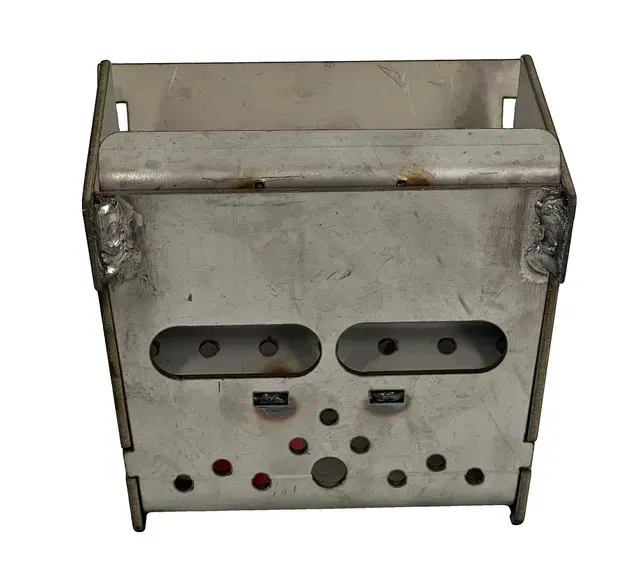 Small metal box with two oval openings and several colored buttons or holes on the front.