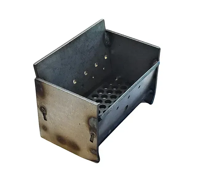 Small metal charcoal grill with perforated grate and side handles, isolated on white background