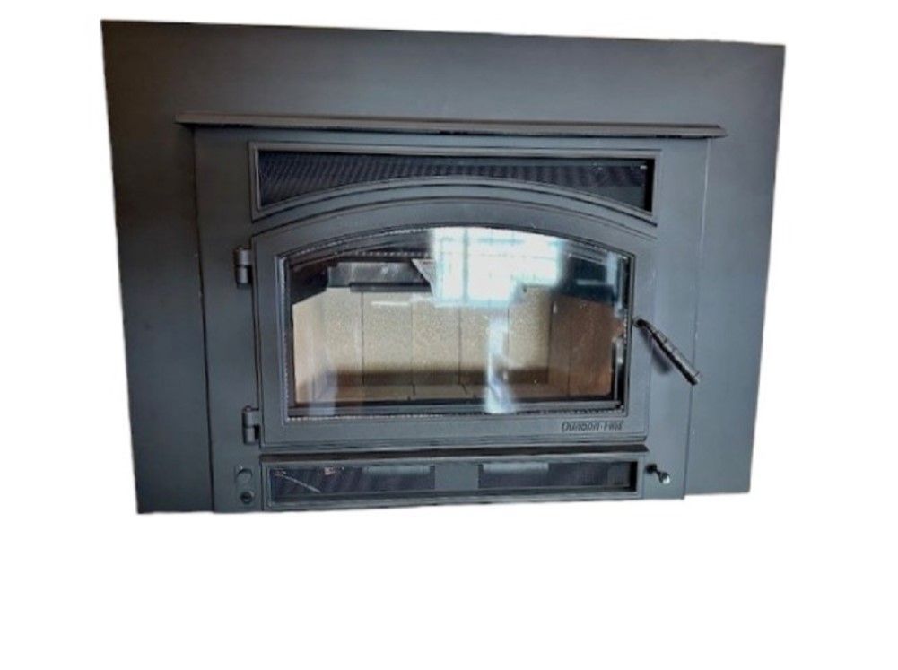 Black metal wood-burning stove with glass door and handle built into a wall.