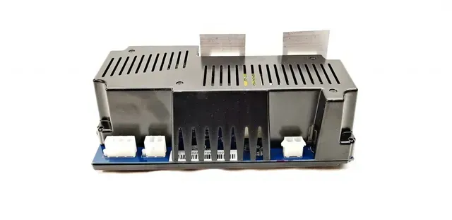Black electronic module with vents, connectors, and white plugs on a blue baseplate