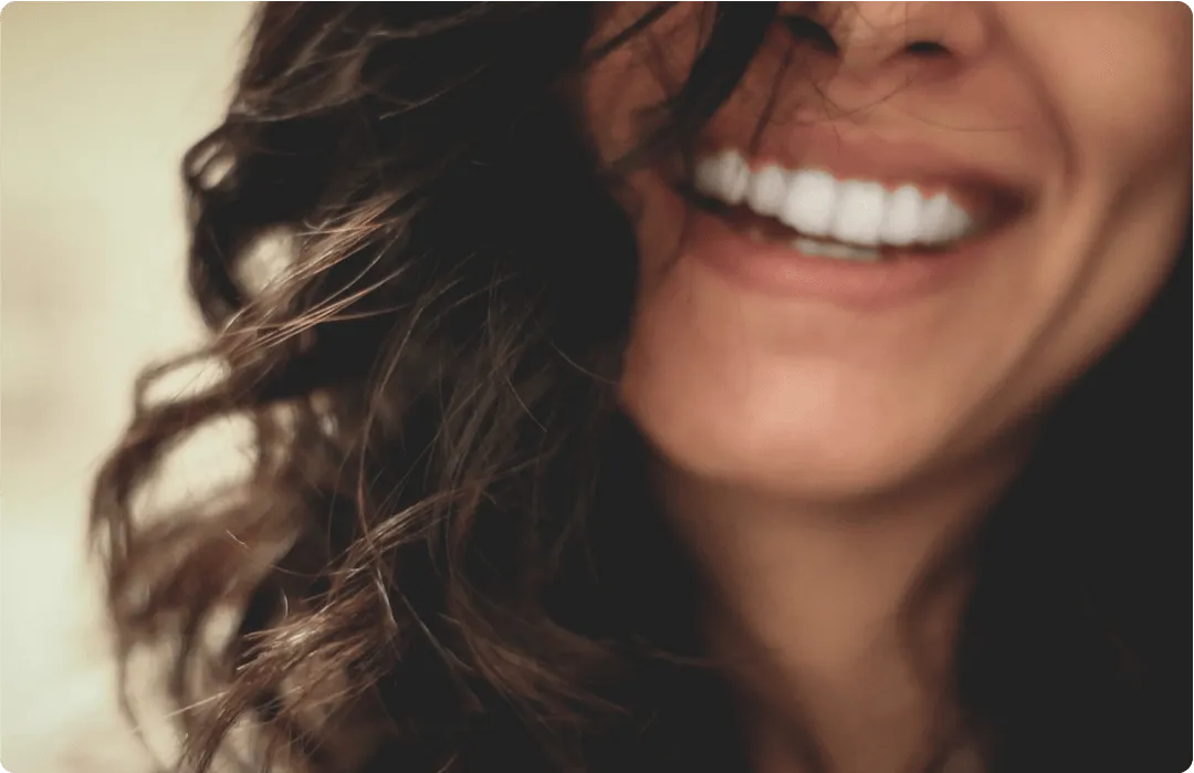 A close up of a woman 's face smiling with her hair blowing in the wind