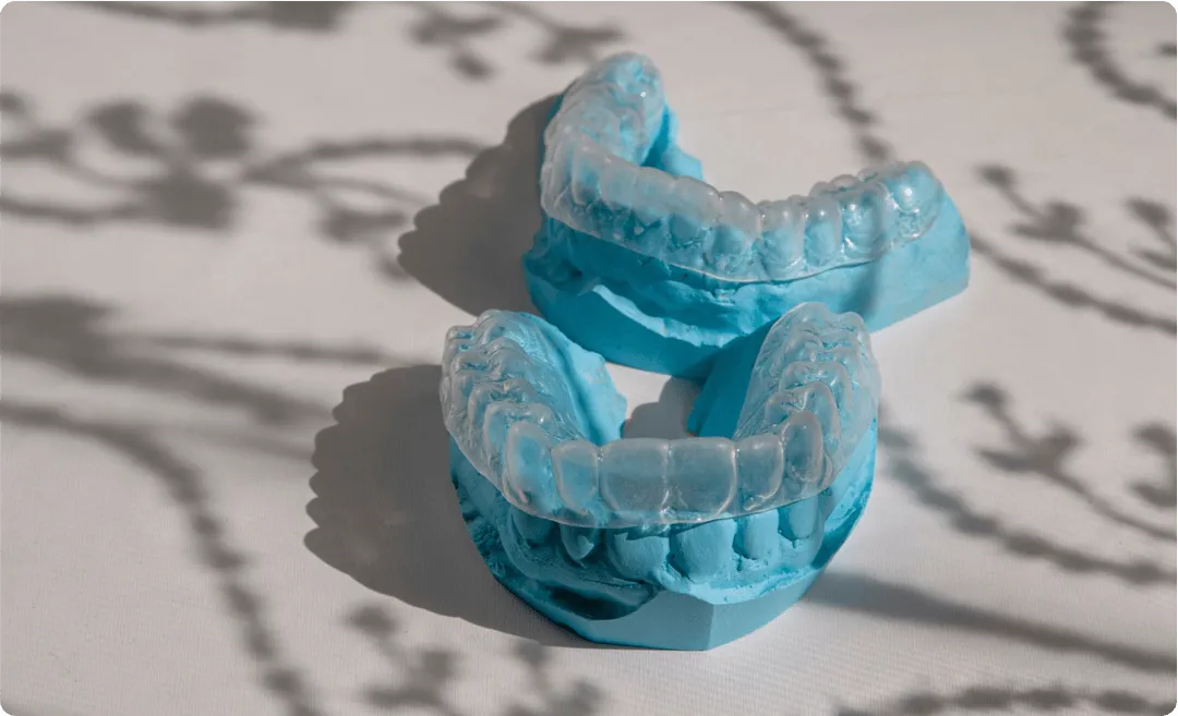 A pair of dental molds with Invisalign fitted on them are sitting on top of each other on a table