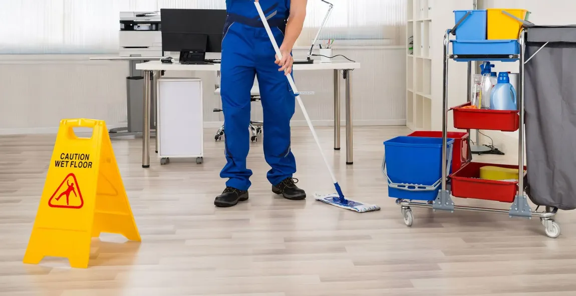 Janitor mopping office floor next to a 