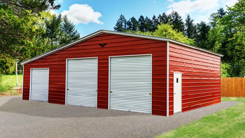 Red metal garage with two garage doors, a side door, and gravel driveway.