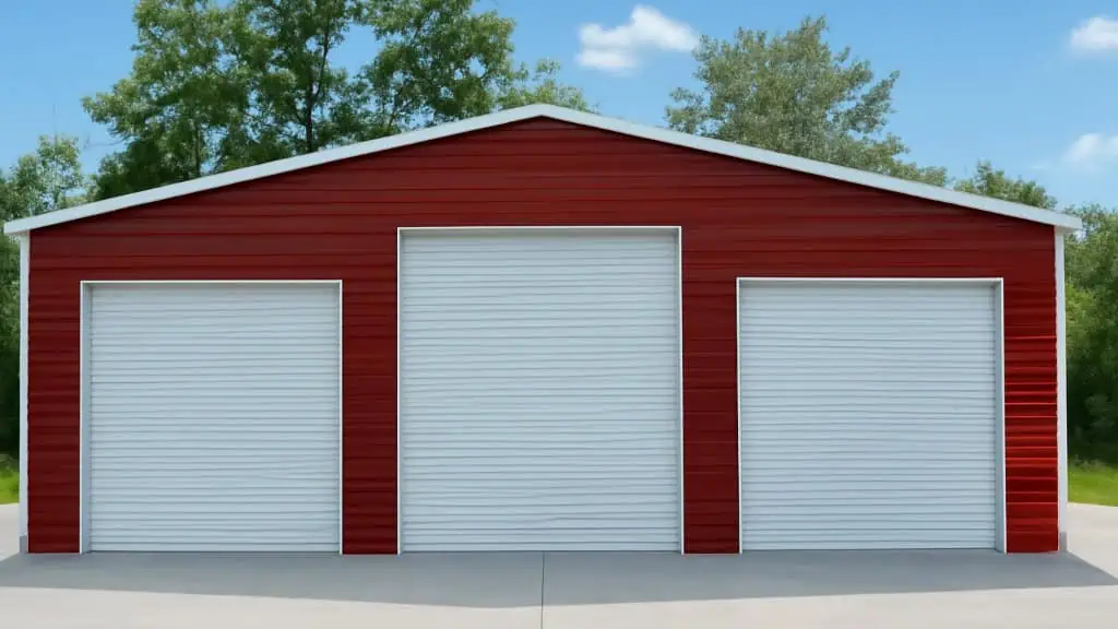 Red metal garage with three white roll-up doors against a blue sky.