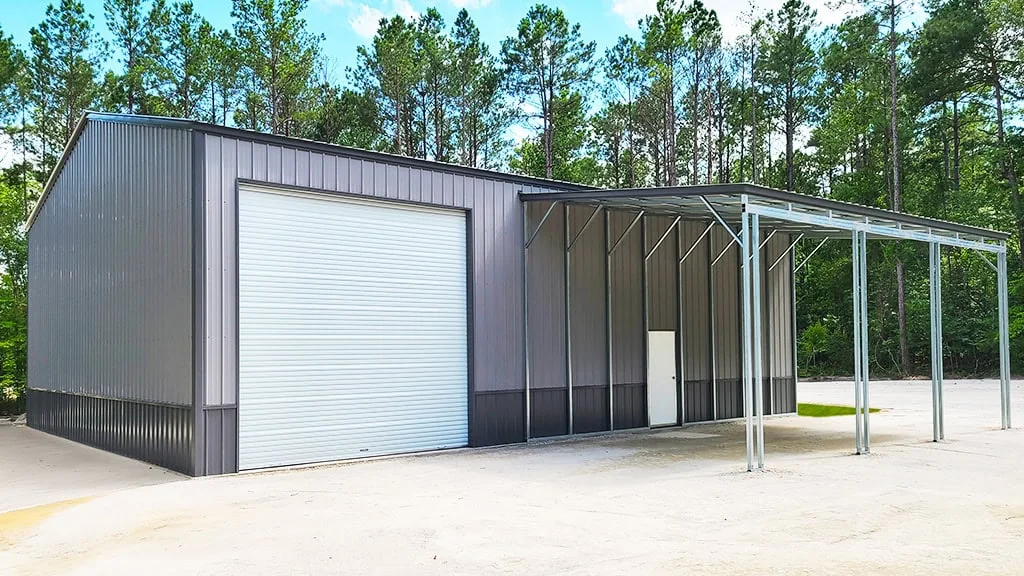 Steel building with large garage door, small door, and open carport under a blue sky.